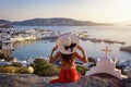 A elegant tourist woman in a red dress enjoys the view over the city of Mykonos island Royalty Free Stock Photo