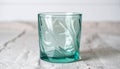 Elegant Turquoise Glass Cup with Swirl Pattern on Textured Cloth Background Royalty Free Stock Photo
