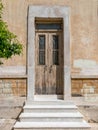 An elegant vintage house entrance with marble stairs and a wooden door.