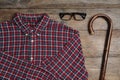 Elegant walking cane, glasses and shirt on wooden table, flat lay