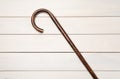 Elegant walking cane on white wooden table, top view