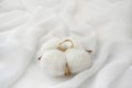 Elegant wedding concept. Golden ring with cotton flower pillow on white silk background.