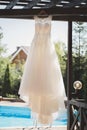Elegant wedding dress in a wooden gazebo on the background of the pool during the morning gathering of the bride.