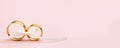 Elegant Wedding or Engagement banner background - pair of golden wedding rings on light pink background Royalty Free Stock Photo