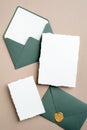 Elegant wedding invitation cards mockups and green envelopes on brown background