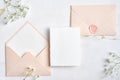 Elegant wedding stationery set. Wedding invitation card mockup, pastel pink wedding envelopes, flowers on stone table. Flat lay,