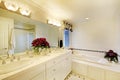 Elegant white bathroom interior decorated with flowers.