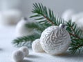 Elegant white Christmas bauble with intricate embossed patterns resting on snowy surface beside fresh evergreen branches and Royalty Free Stock Photo