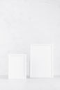 Elegant white empty rectangle photo frames standing on white wood table in simplicity delicate modern minimal soft light interior. Royalty Free Stock Photo