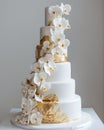 Elegant white and gold wedding cake adorned with white flowers and gold leaves