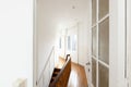 Elegant white hallway furnished with a wooden railing and a single armchair Royalty Free Stock Photo