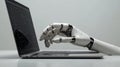 Elegant white robotic hand working on a laptop, illustrating the concept of technological evolution Royalty Free Stock Photo