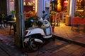 Elegant white scooter parked near a cafe, night