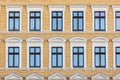 Elegant windows set facade vibrant yellow brick building, showcasing architectural symmetry and beautiful vintage