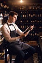 Elegant wine seller holding a bottle of wine and reading label in a wine store Royalty Free Stock Photo