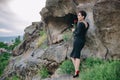 Elegant woman with black dress standing next to the ancient cliffs