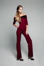 Elegant woman in bordo overall with bare shoulders and high heels.