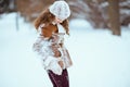 elegant woman in brown hat and scarf shaking snow off clothes