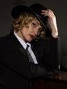 Elegant woman in business suit with a hat poses on a dark background, stylized retro portrait Royalty Free Stock Photo