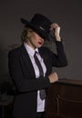 Elegant woman in business suit with a hat poses on a dark background, stylized retro portrait Royalty Free Stock Photo