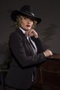 Elegant woman in business suit with a hat poses on a dark background, stylized retro portrait Royalty Free Stock Photo