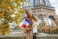 Elegant woman on embankment near Eiffel tower showing flag Royalty Free Stock Photo