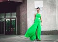 Elegant woman in green dress posing against a concrete wall Royalty Free Stock Photo