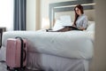 Elegant woman lying dressed on bed with laptop at the hotel room. Royalty Free Stock Photo