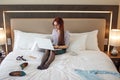 Elegant woman lying dressed on bed with laptop at the hotel room. Royalty Free Stock Photo