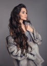 Elegant woman in mink fur coat isolated on gray studio background. Fashion Brunette Girl in Luxury Winter outerwear