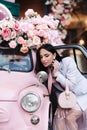 Elegant woman model look in pink vintage car mirror touch earring. Attractive brunette lady outdoor Royalty Free Stock Photo