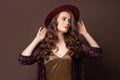 Elegant woman in plaid shirt and fedora hat posing on brown background Royalty Free Stock Photo