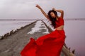 Elegant Woman In Red Silky Dress Walking By A Salt fantastic Lake At Sunset.