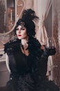 Elegant woman in retro style of the 20s, lady flapper in a black dress, dark hair and a bandage, feather boa, long Royalty Free Stock Photo