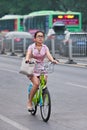 Elegant woman rides a public share bike with bus on background, Beijing, China Royalty Free Stock Photo