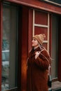 Elegant woman with scarf and winter gloves looking at boutique showcase