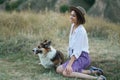 Elegant woman sitting on grass at autumn meadow with welsh corgi puppy Royalty Free Stock Photo