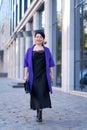 An elegant woman in a stylish outfit poses on a city street Royalty Free Stock Photo