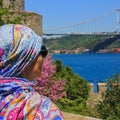 Elegant woman traveler looking to Fatih Sultan Mehmet Bridge on Bosphorus in Rumeli Hisari Fortress,Istanbul,Turkey Royalty Free Stock Photo