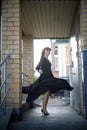 Elegant Woman Twirling in Black Dress on Staircase. A woman in a twirling black dress captured mid-movement on the porch Royalty Free Stock Photo