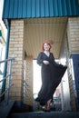 Elegant Woman Twirling in Black Dress on Staircase. A woman in a twirling black dress captured mid-movement on the porch Royalty Free Stock Photo