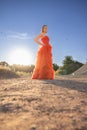 Elegant Woman in Vibrant Red Gown Against Sunset Sky