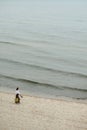 Elegant woman walking along sea with shoes and bag in hands Royalty Free Stock Photo