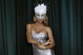 Elegant Woman is wearing Carnival Feather Mask and sequin silver evening dress and is posing on dark velvet background. Masquerade Royalty Free Stock Photo