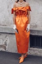 Elegant woman wearing orange long dress, black bag and white gloves