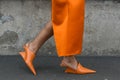 Elegant woman wearing orange long dress, black bag and white gloves