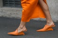 Elegant woman wearing orange long dress, black bag and white gloves