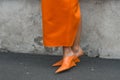 Elegant woman wearing orange long dress, black bag and white gloves