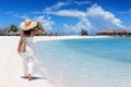 A elegant woman in a white dress walks down a tropical paradise beach Royalty Free Stock Photo