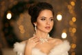 Elegant woman in white fur. Winter fashion portrait of Beautiful bride young with diamond earrings and necklace jewelry set. Royalty Free Stock Photo
